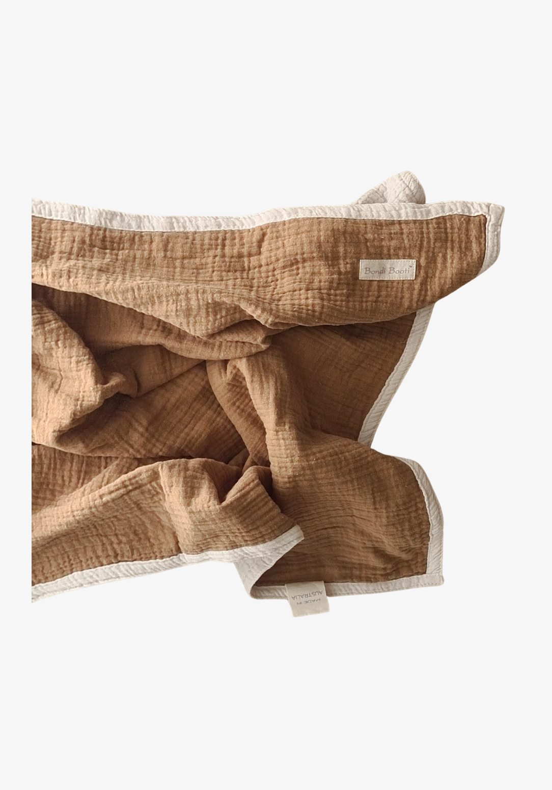 Reversible baby blanket in warm brown and white organic cotton, with visible Bondi Booti and “Made in Australia” labels, displayed on a neutral fabric background.