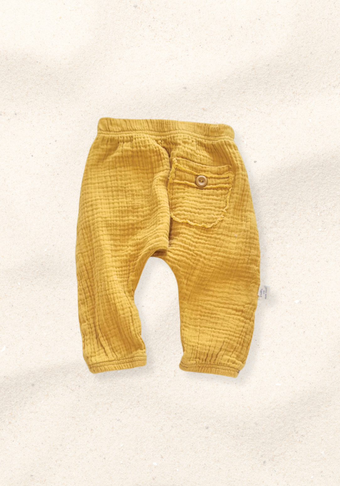 Toddler harem pants in mustard yellow made from organic cotton with a wooden button and soft elastic waistband