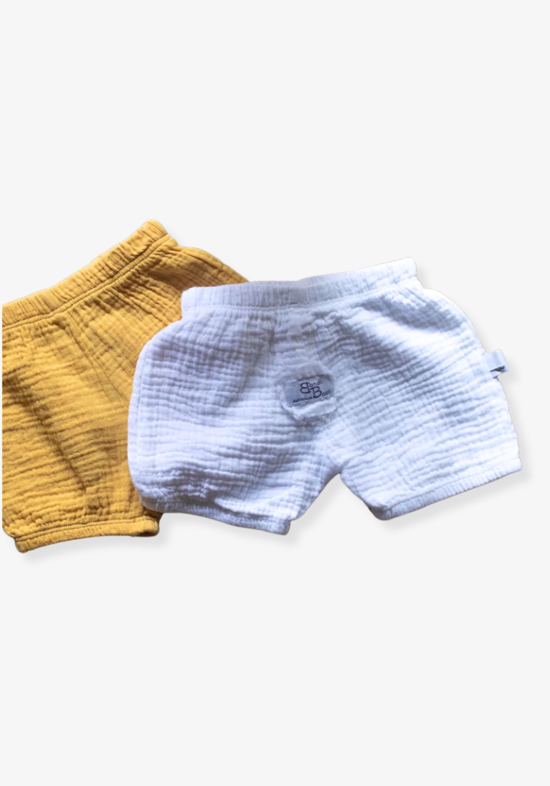 Minimalist white baby bloomers made from breathable organic cotton, displayed on a grey background with elastic details