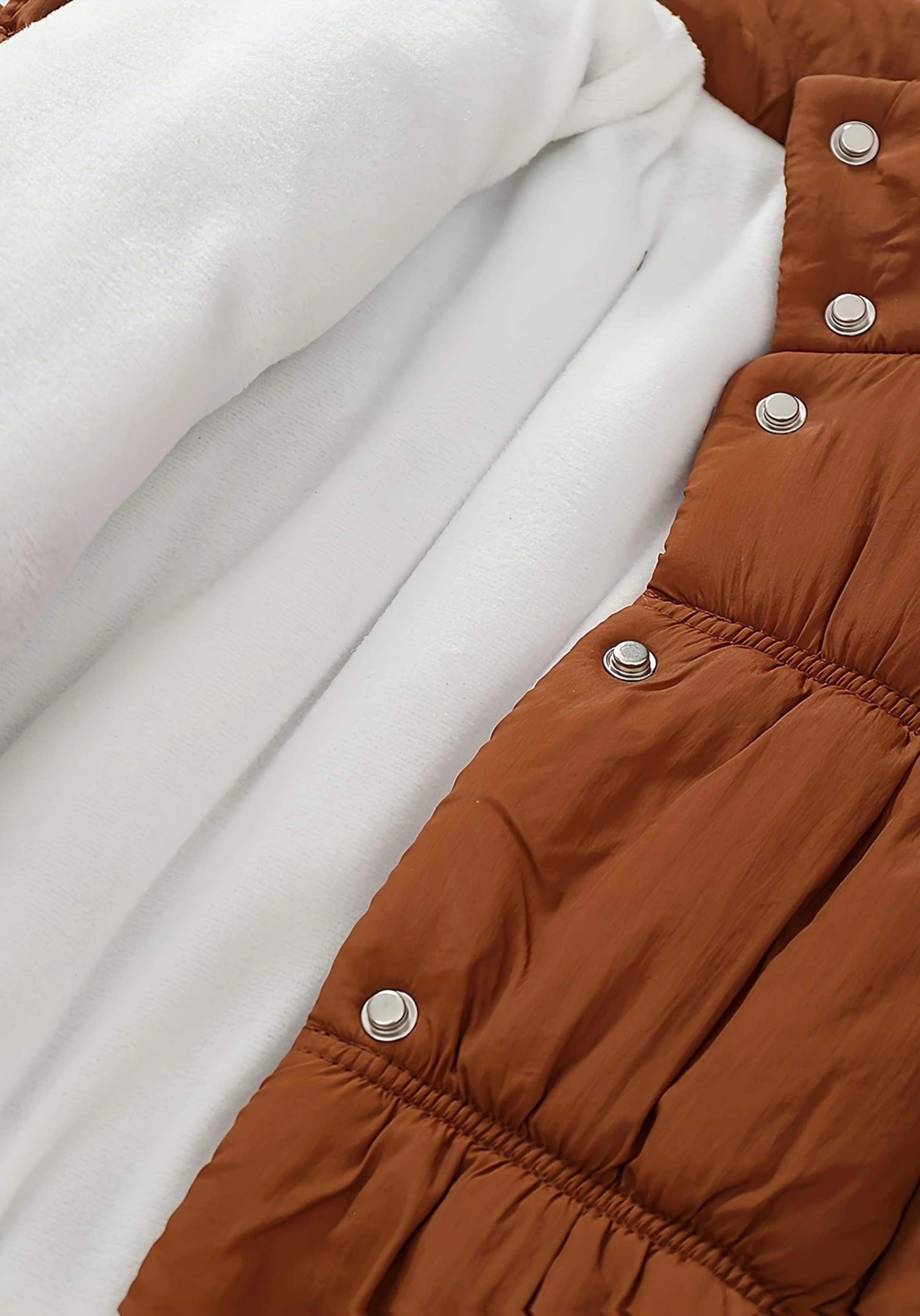 Close up view of toddler brown puffer jacket with ruched detailing and high collar
