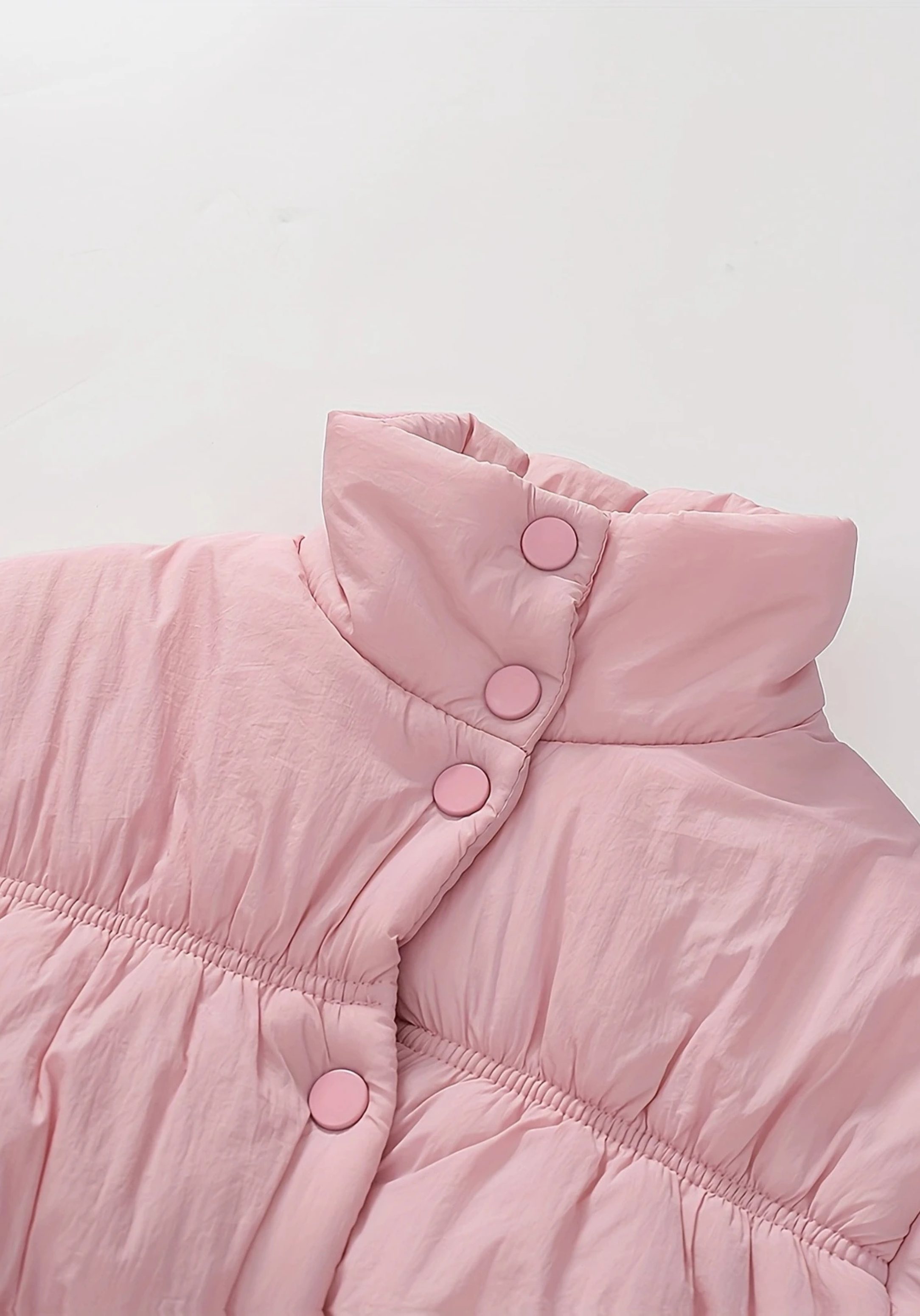 Close up view of toddler pink puffer jacket with ruched detailing and high collar