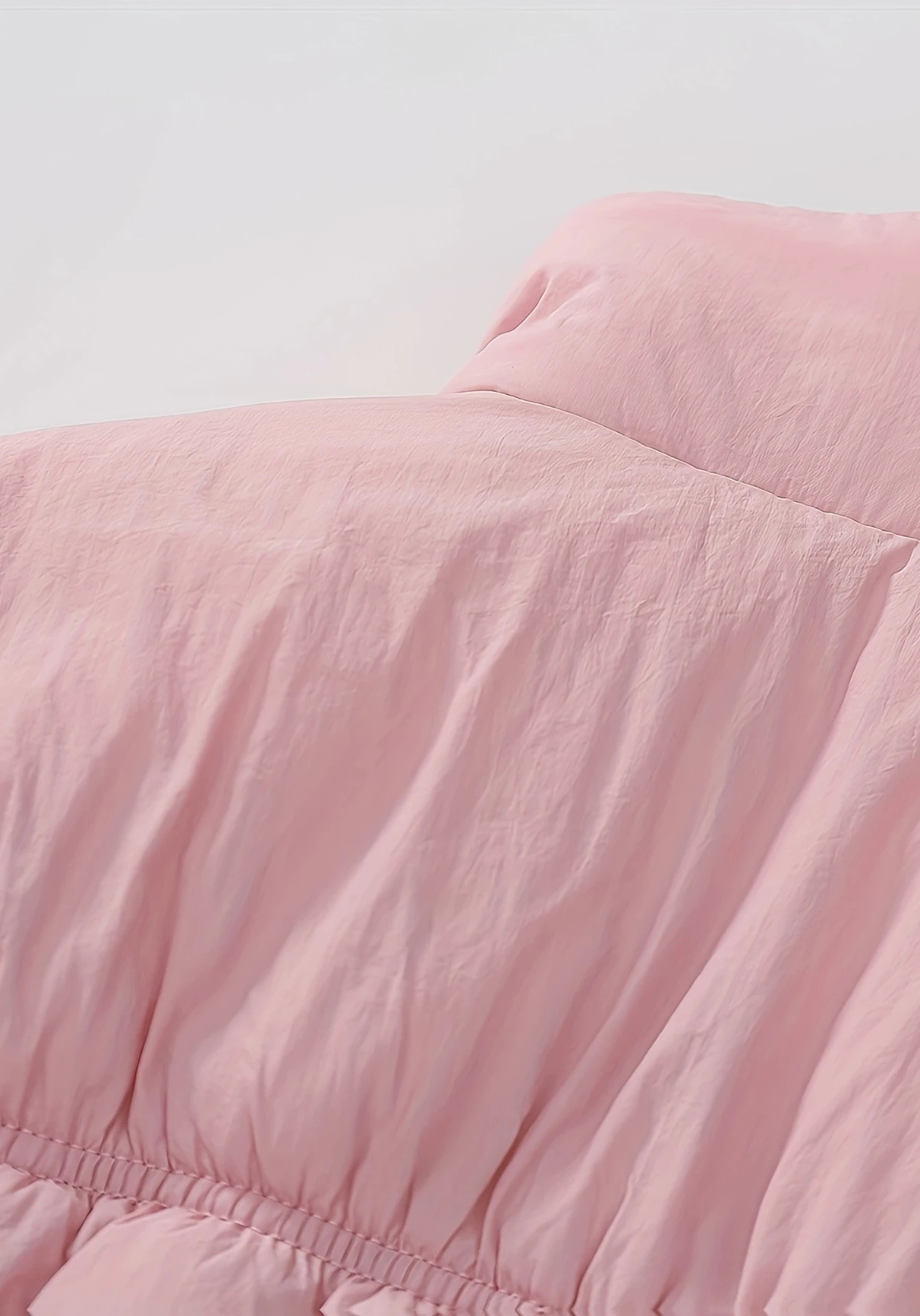 Close up view of toddler pink puffer jacket with ruched detailing and high collar