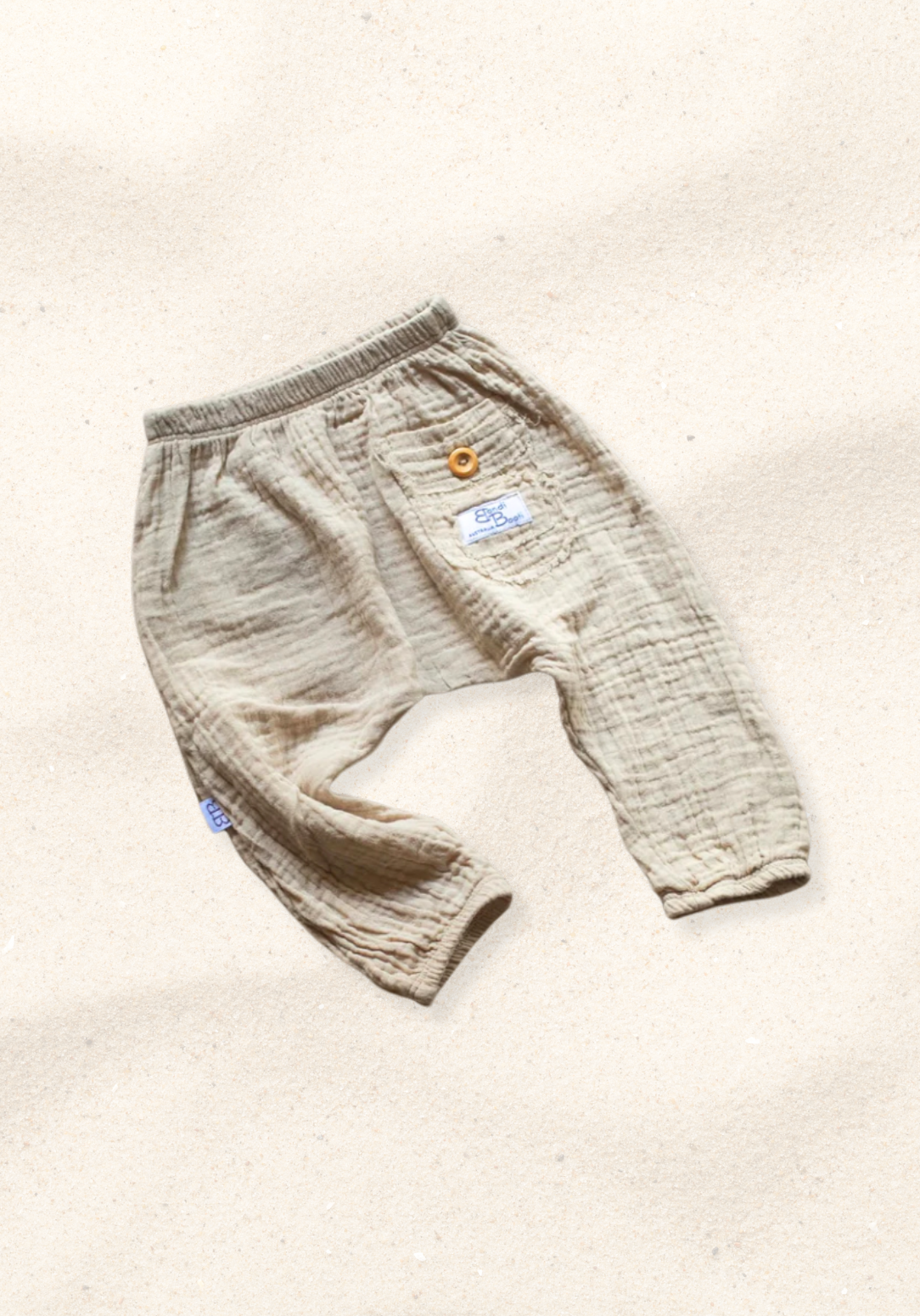 Beige organic cotton toddler harem pants with elastic waistband, wooden button, and back pocket