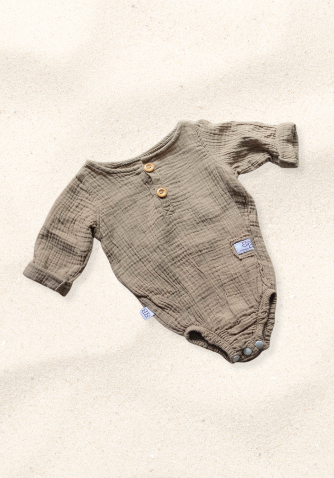 Long sleeve baby romper in mocha color crafted from organic cotton with snap closure and wood button details