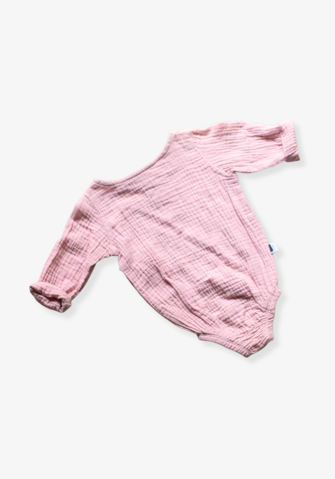 Back view of pink muslin long sleeve baby romper with soft gathered design on grey background