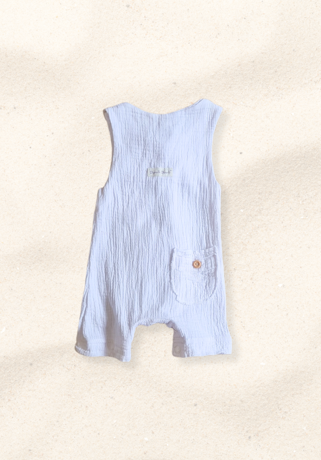 White baby overall onesie made from breathable organic cotton with wooden buttons and crotch snaps.
