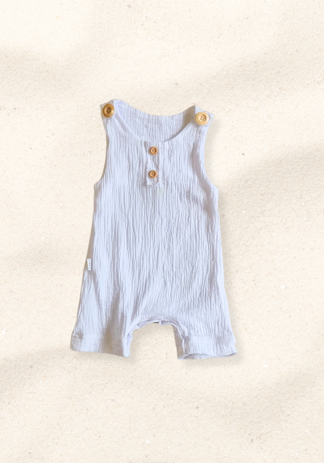 White baby overall onesie made from breathable organic cotton with wooden buttons and crotch snaps.